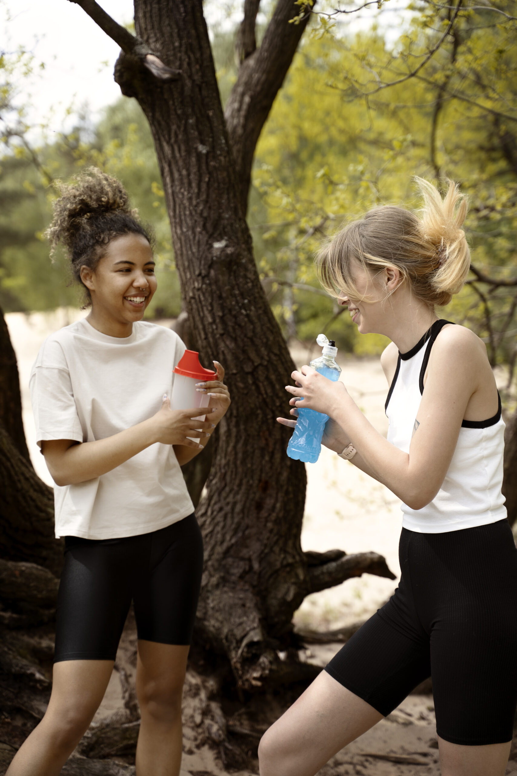 Deux femmes en tenue de sport dans une forêt buvant de l'eau dans une gourde